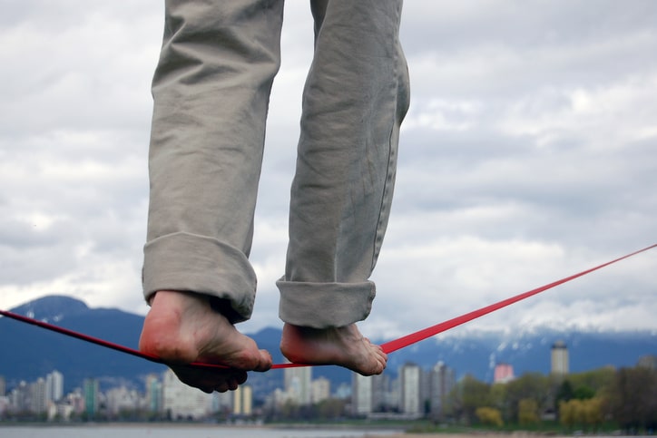 person in slacks walking a tight rope